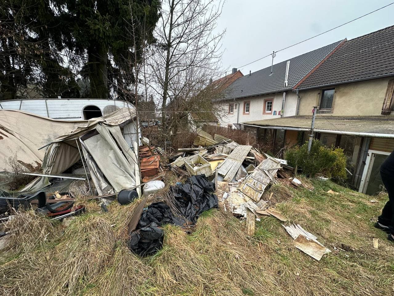 Garten mit Abfall und alten Gartenmöbeln vor der Räumung